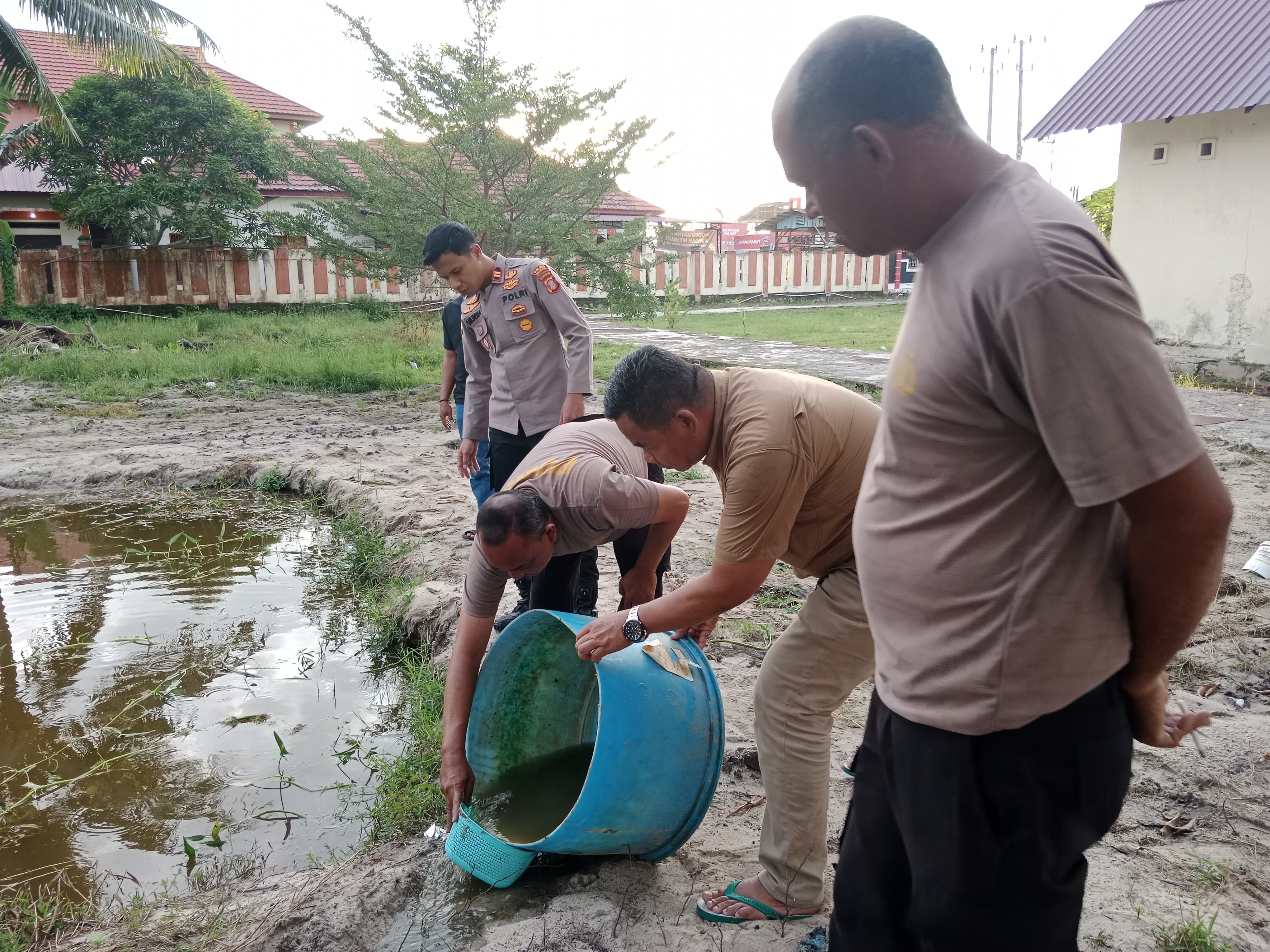 KETAHANAN PANGAN: Kapolsek Samboja IPTU Sarlendra Satria Yudha bersama personel Polsek Samboja melakukan penebaran bibit ikan nila di kolam pekarangan Polsek Samboja, Jumat (13/12).