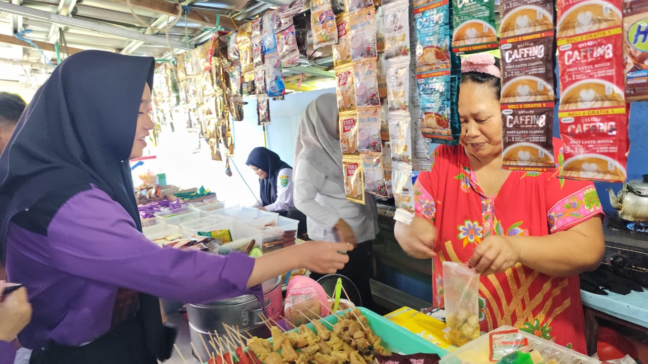 JUALAN: Diana (kanan) melayani siswi SMK 16 Samarinda yang jajan di kantin yang dikelolanya, Rabu (15/1). (FOTO: DENNY SAPUTRA)