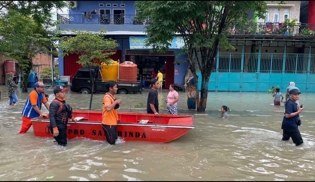 KIAN PARAH: Beberapa warga di Jalan Poros Perum Bengkuring Raya Kelurahan Sempaja Timur, beraktivitas menggunakan perahu darurat, karena ketinggian banjir mencapai berkisar 30-70 centimeter.