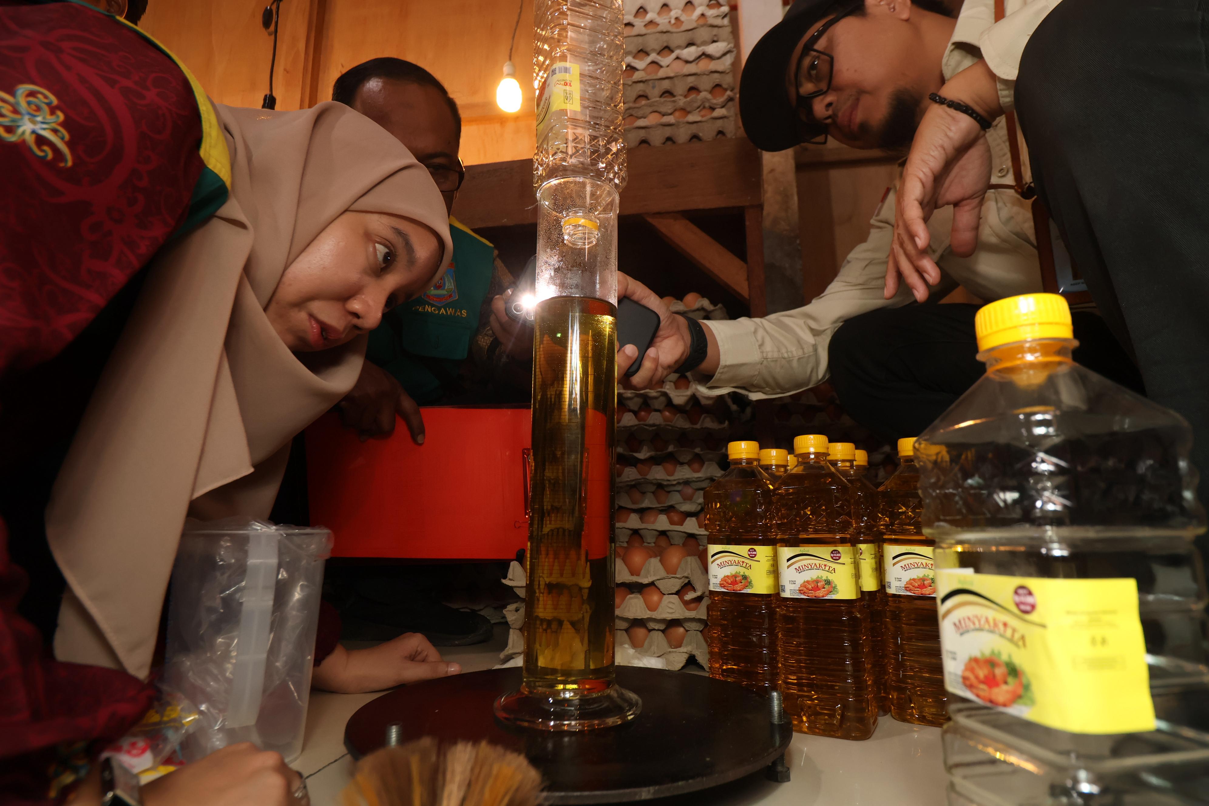PRAKTIK CURANG: Petugas dari Dinas Perdagangan Balikpapan saat mengecek isi minyak goreng Minyakita yang tak sesuai takaran. (ANGGI PRADITHA/KP)