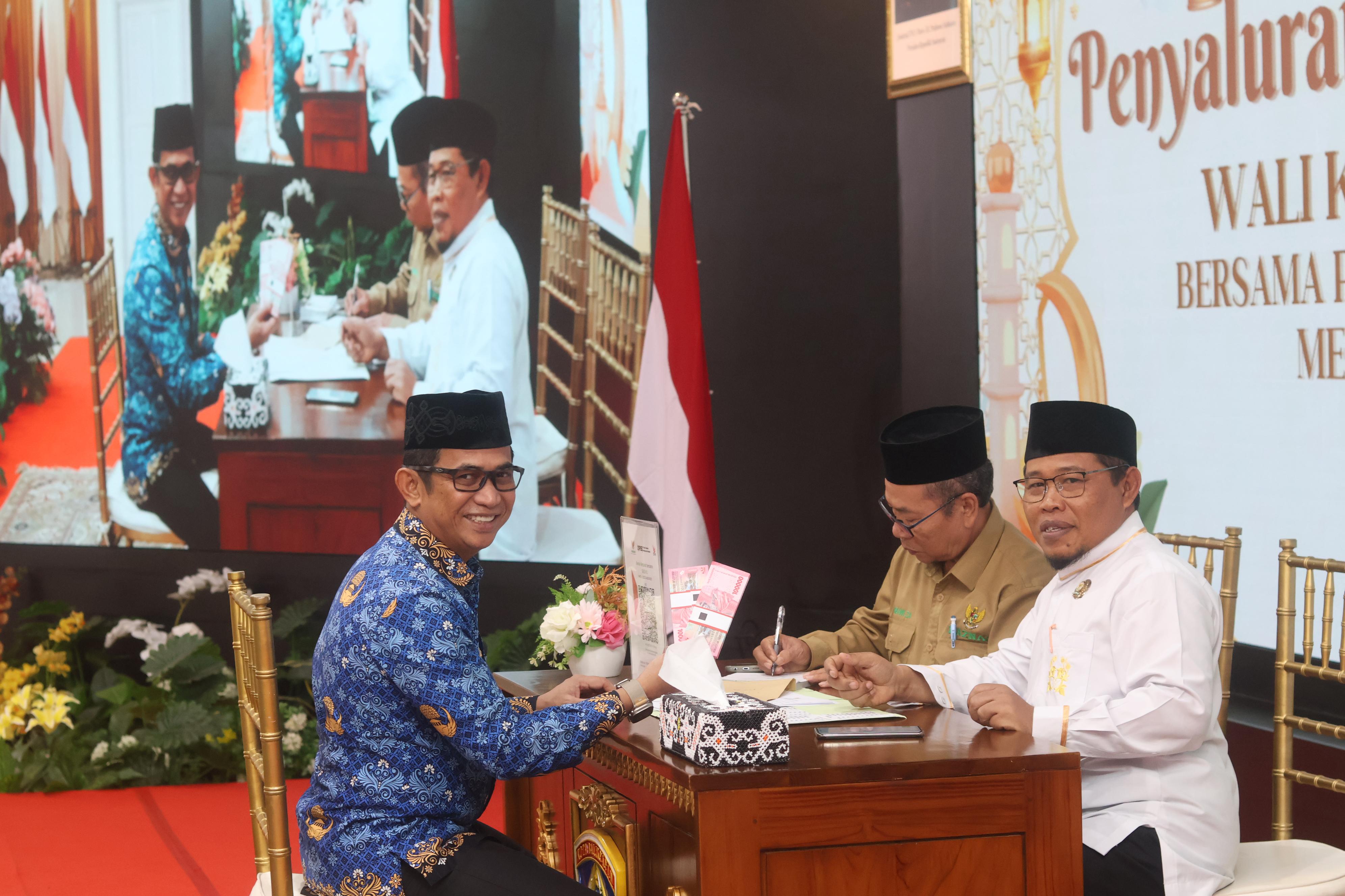 TUNAIKAN KEWAJIBAN: Rahmad Mas&rsquo;ud (kiri) saat menyalurkan zakat yang diterima Abdul Rosyid Bustomi di Aula Balai Kota Balikpapan, Senin (17/3). (ANGGI PRADITHA/KP)