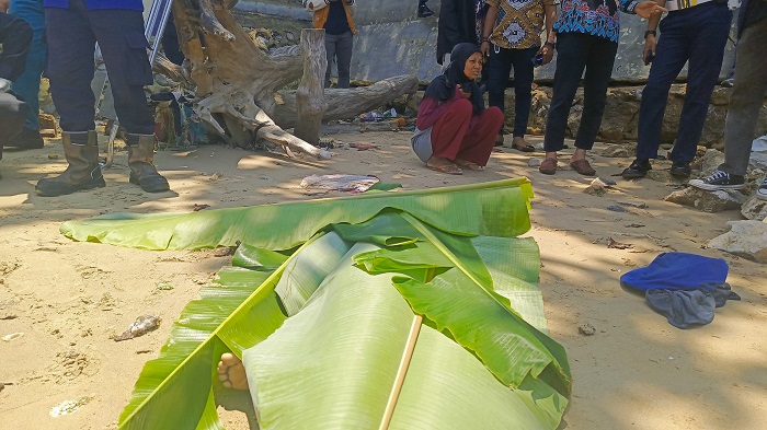 TERMENUNG : Nia (baju merah) saat berada di hadapan jenazah anaknya yang meninggal dunia disengat ubur-ubur, Kamis (27/3).