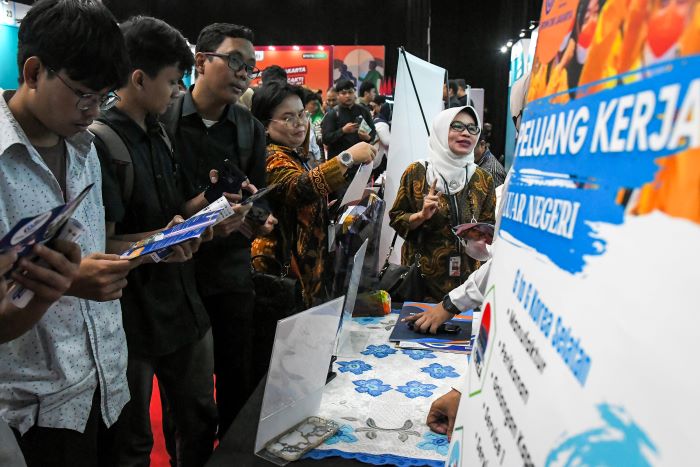 Pencari kerja memeriksa informasi di bursa kerja yang berlangsung di Jakarta.  Para pencari kerja didorong melirik potensi pekerjaan di luar negeri. (JAWA POS)