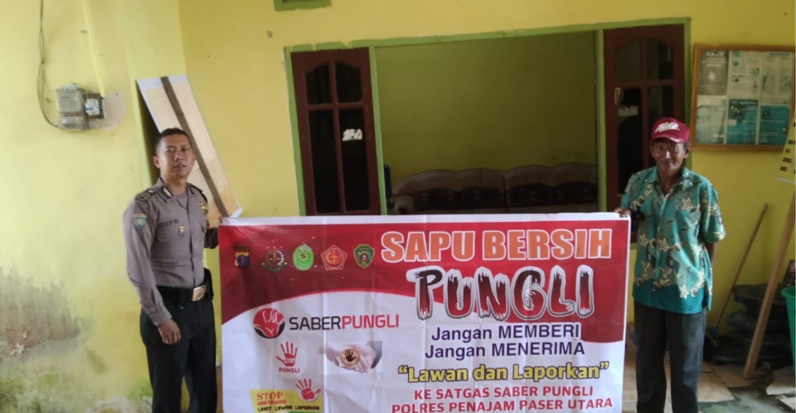 LAWAN: Personel kepolisian Polres PPU saat menunjukkan baliho yang berisi peringatan kepada warga masyarakat terhadap bahayanya pungli. Warga diminta melawan dan melaporkan.