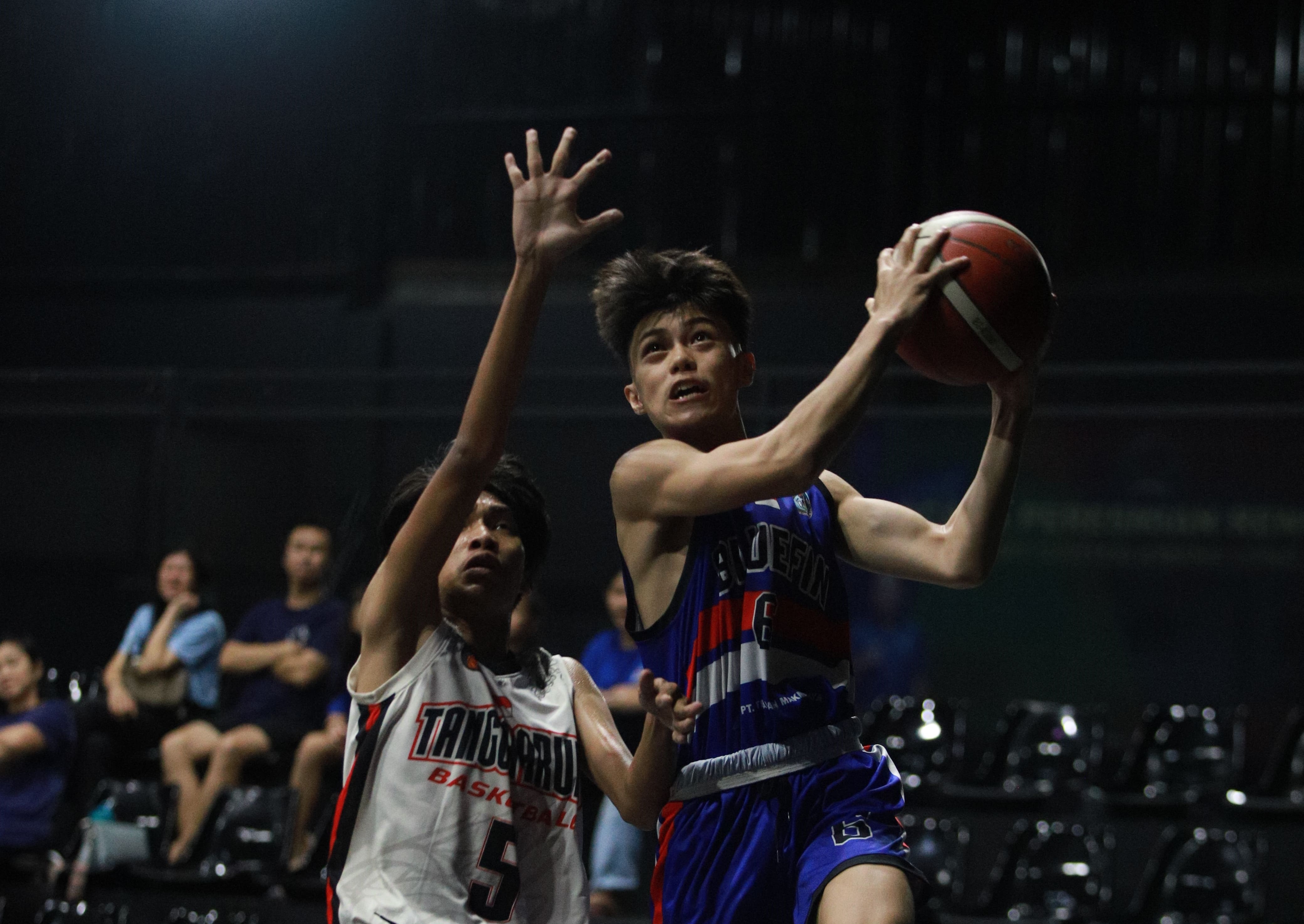 Pemain Bluefin Samarinda (biru) berusaha mencetak poin saat berhadapan dengan Tangga Arung di KBL U1-6 pekan ke-5.