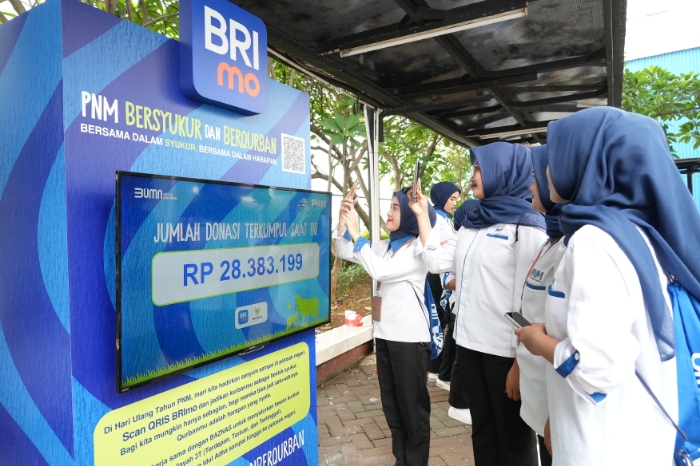 Karyawan PNM berpartisipasi dalam program kurban digital dengan memindai QRIS donasi.