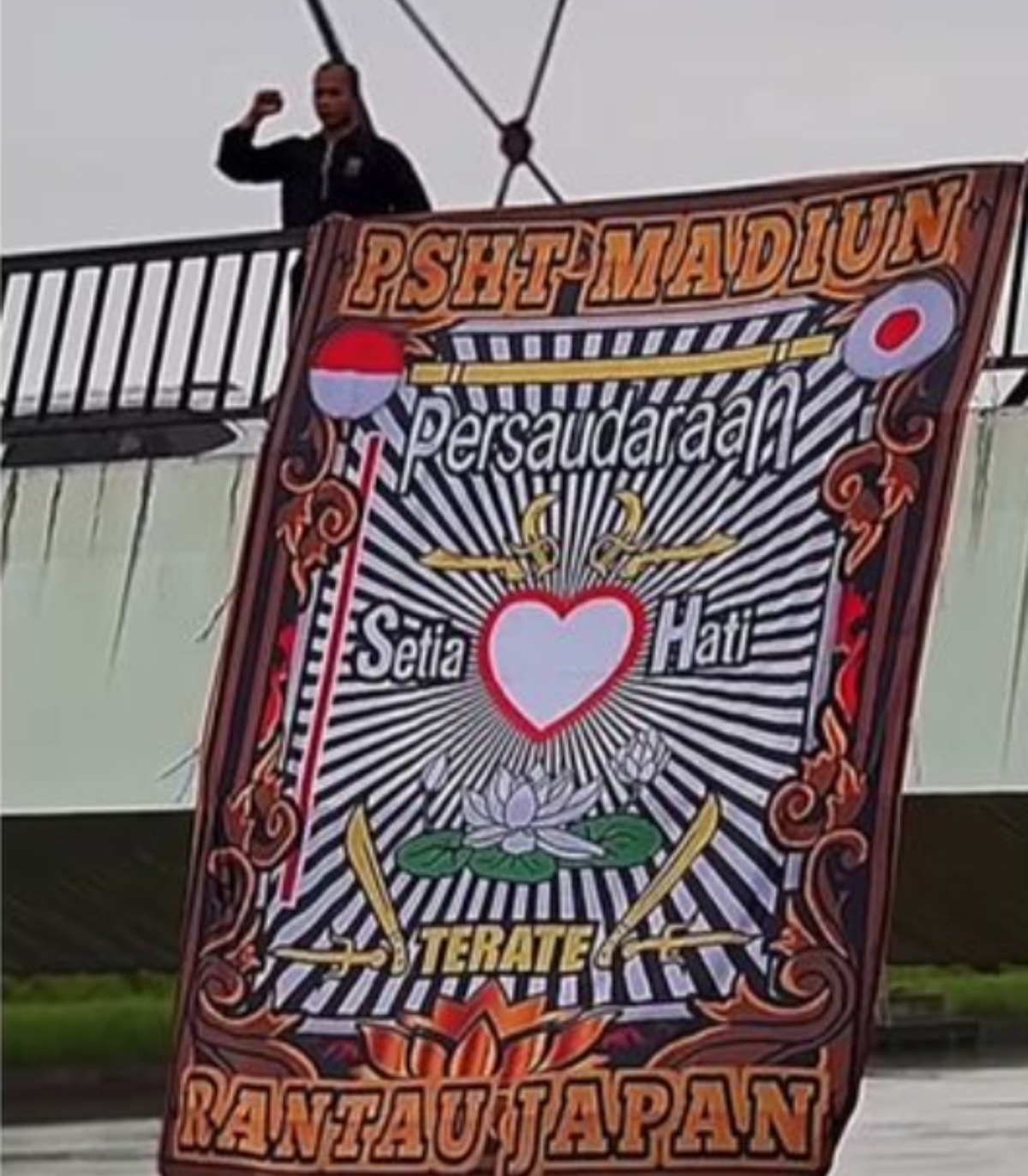 Foto tangkapan layar video PSHT cabang Jepang ketika membentangkan spanduk di sebuah jembatan di Jepang.
