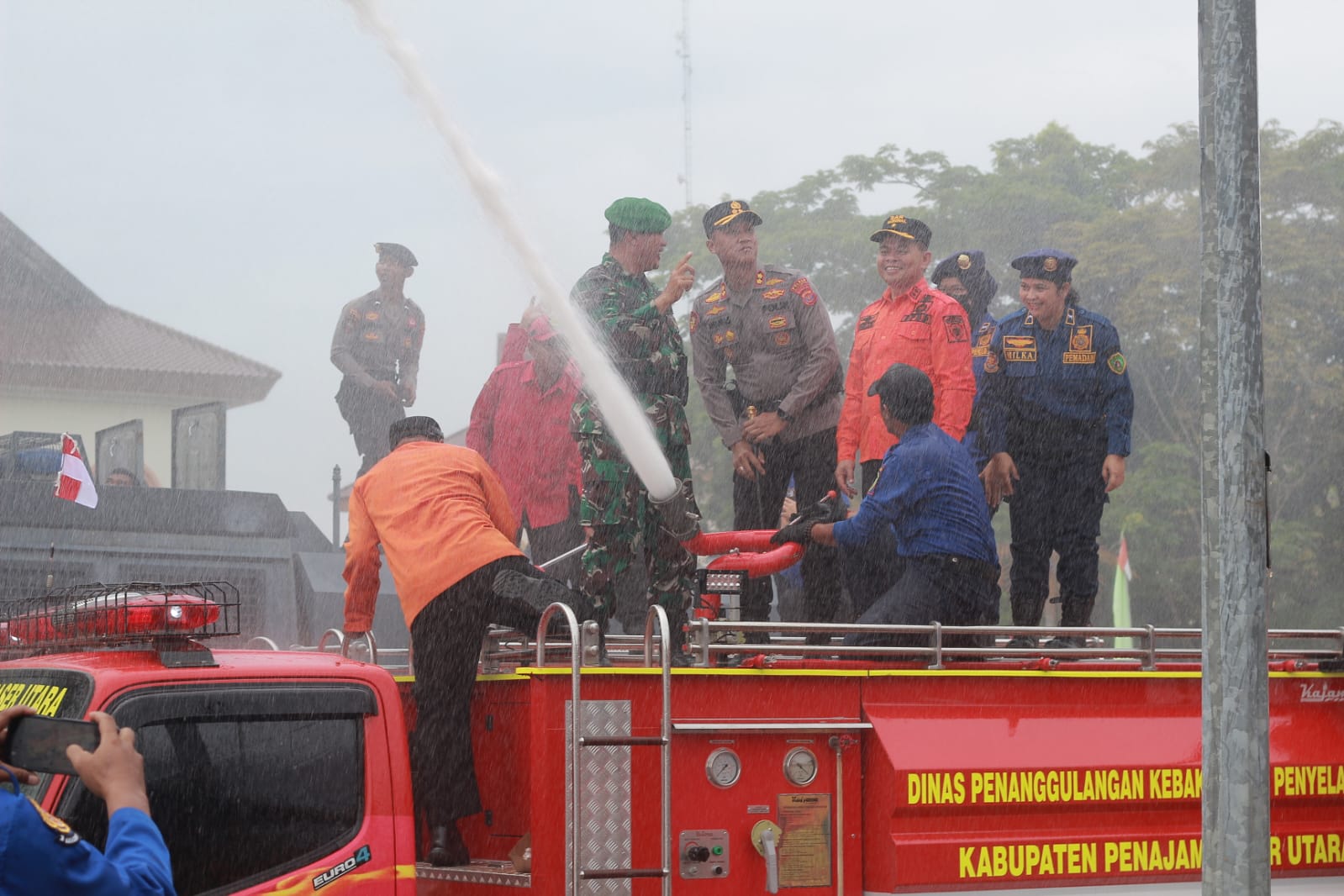 Tohar bersama jajaran FKPD mengguyur para personel yang melaksanakan simulasi penanganan kebakaran dari atas truk tangga aerial.