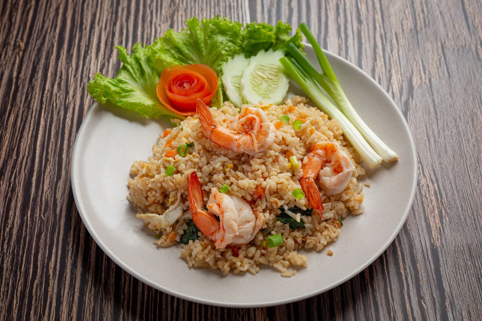 Sepiring nasi goreng, lengkap dengan topping udang dan sayur.