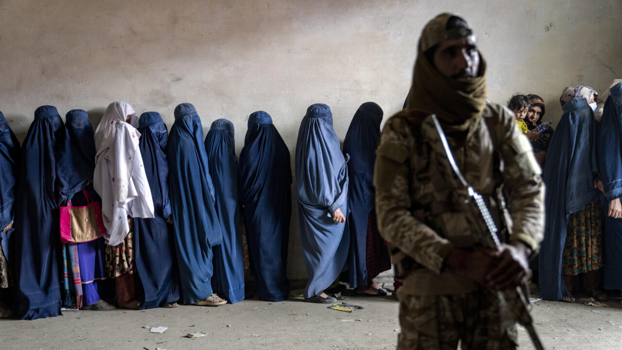 Seorang pejuang Taliban berjaga saat perempuan antre menerima bantuan pangan di Kabul, Afghanistan