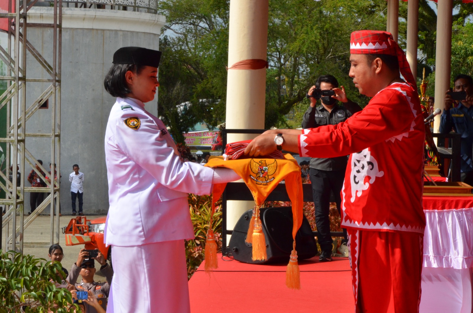 Bupati Kutai Barat, Frederick Edwin (kanan) saat menyerahkan bendera merah putih untuk dikibarkan.