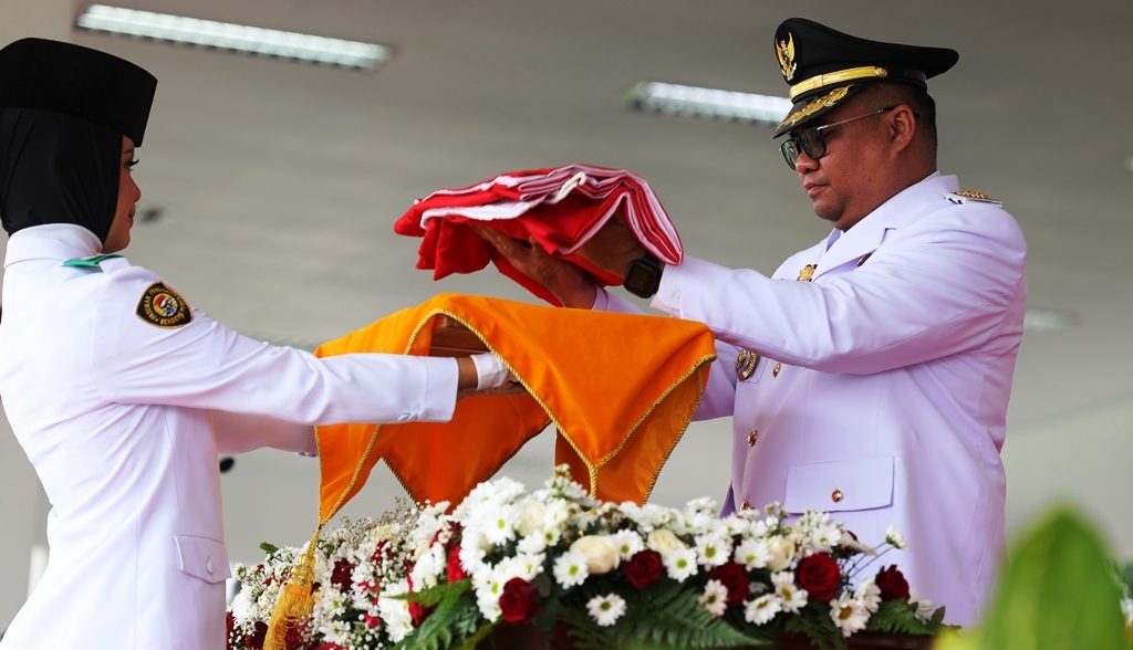 Bupati Kukar Aulia Rahman Basri menyerahkan bendera Merah Putih kepada petugas pembawa baki dalam upacara peringatan HUT ke-80 RI di halaman Kantor Bupati Kukar, Minggu (17/8/2025).