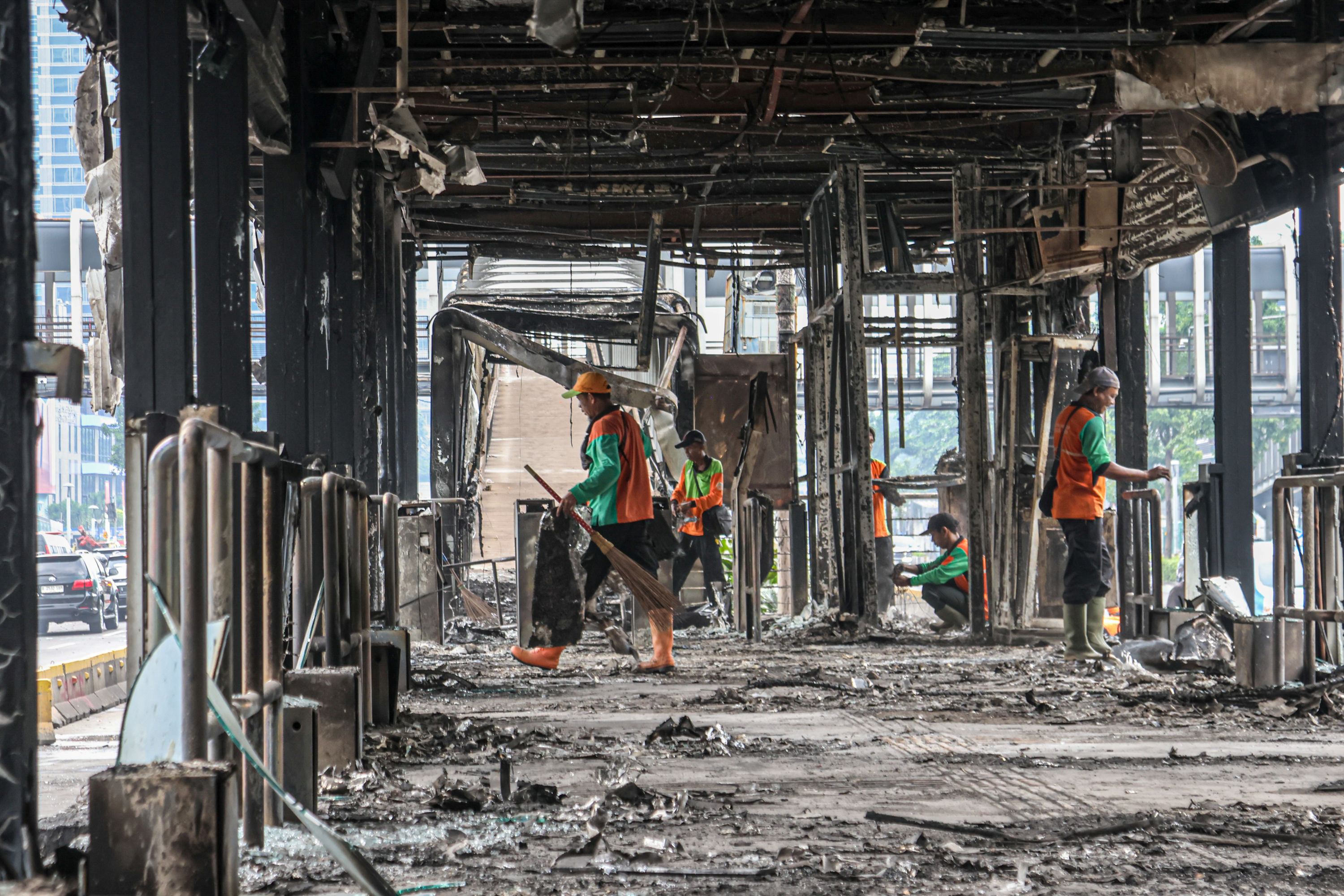 Petugas membersihkan sisa kebakaran di Halte Polda, Jakarta, Sabtu (30/8). (FOTO HANUNG HAMBARA/JAWA POS)
