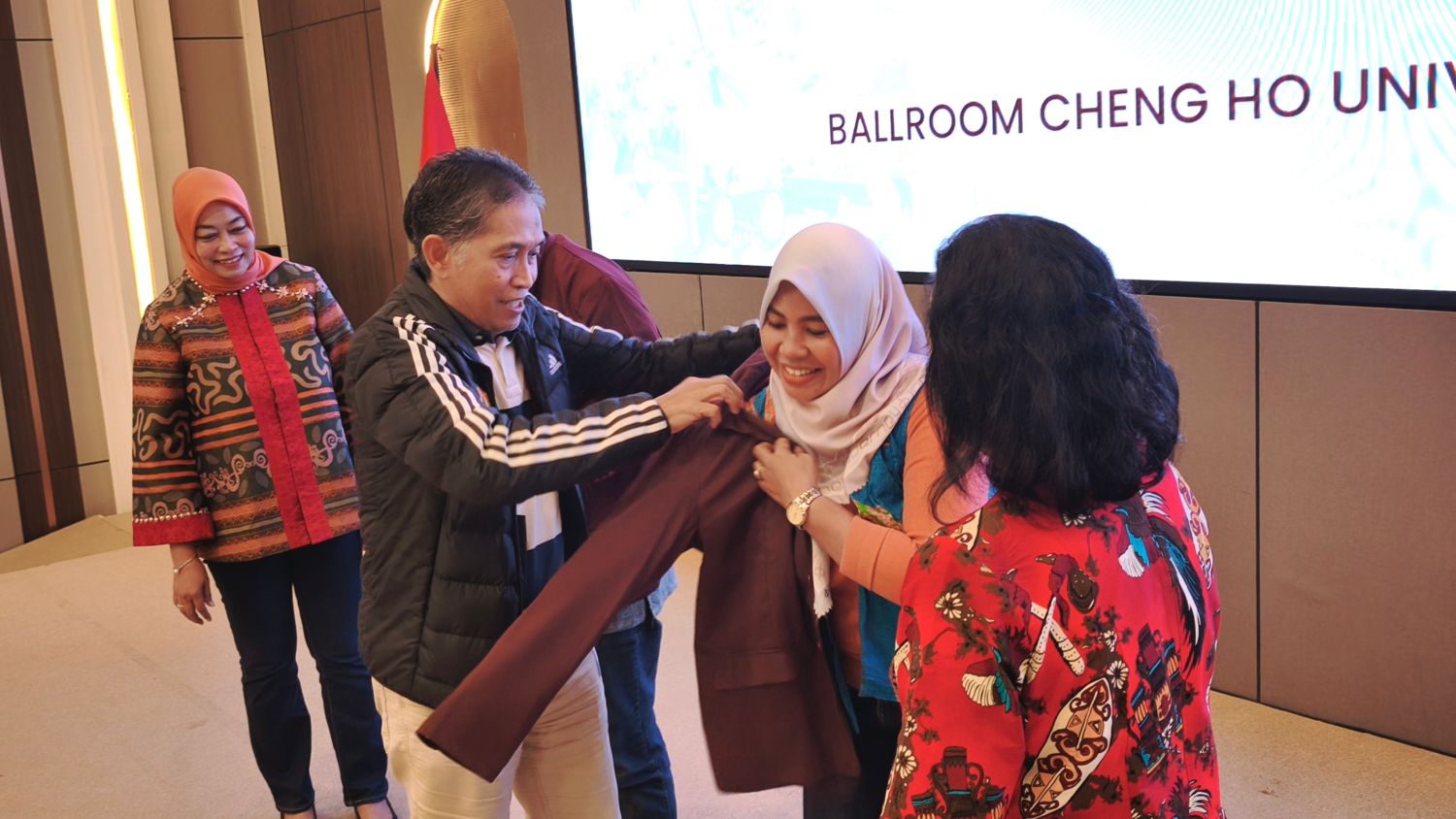 MAHASISWA BARU: Prosesi penyematan jaket almamater Universitas Mulia oleh Agung Sakti Pribadi kepada ketua RT sebagai mahasiswa baru Program Studi Manajemen. Dilanjutkan dengan foto bersama.