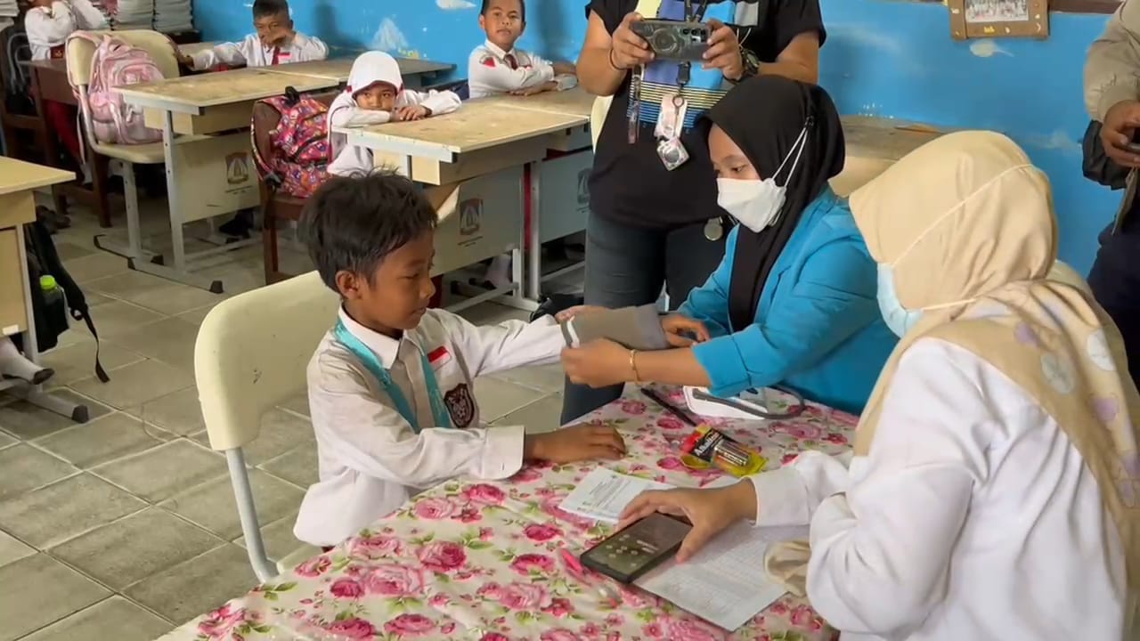 Ilustrasi tenaga medis melakukan cek kesehatan di sekolah.