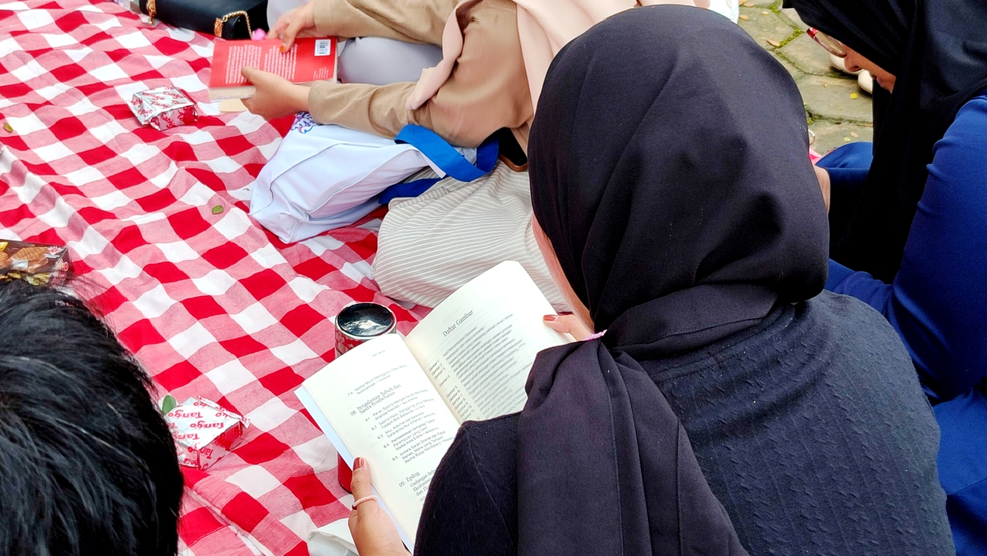 Baca buku sambil piknik.
