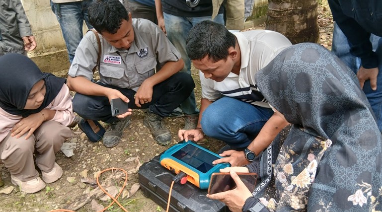 1. Tim Geofisika Universitas Mulawarman bersama warga memperhatikan hasil pemetaan bawah tanah menggunakan alat Audio Domain Magnetotelluric (ADMT).
