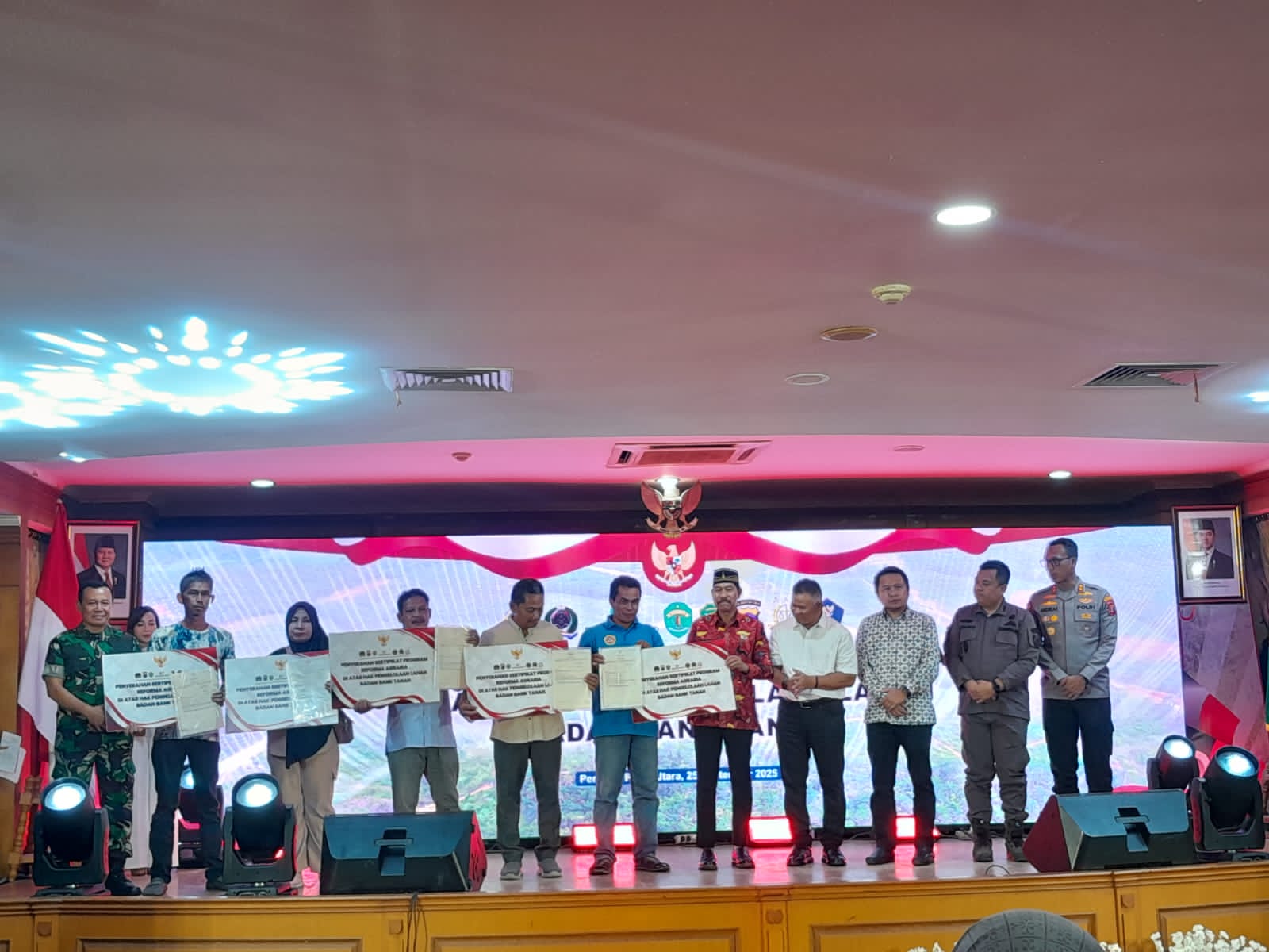Abdul Waris Muin (batik merah) menyerahkan sertifikat tanah kepada warga.