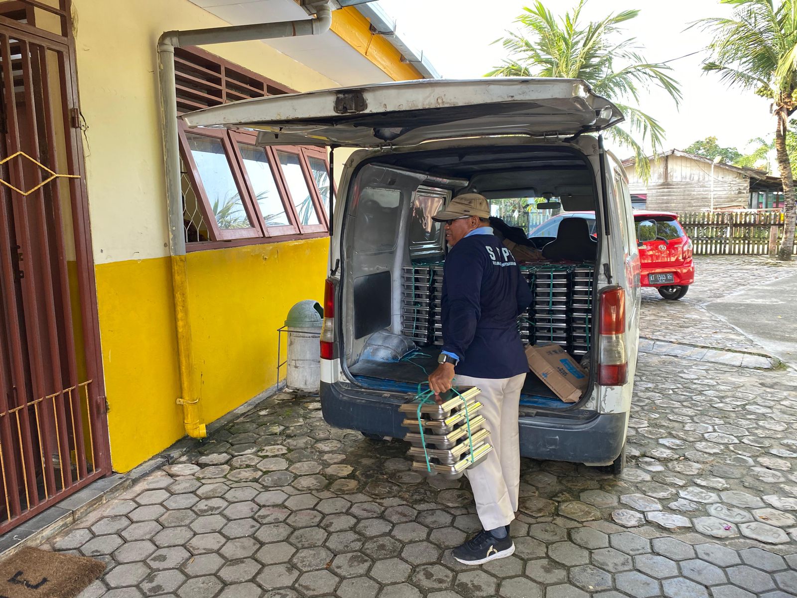 Petugas dari SPPG memberikan ompreng berisi paket MBG ke salah satu sekolah.