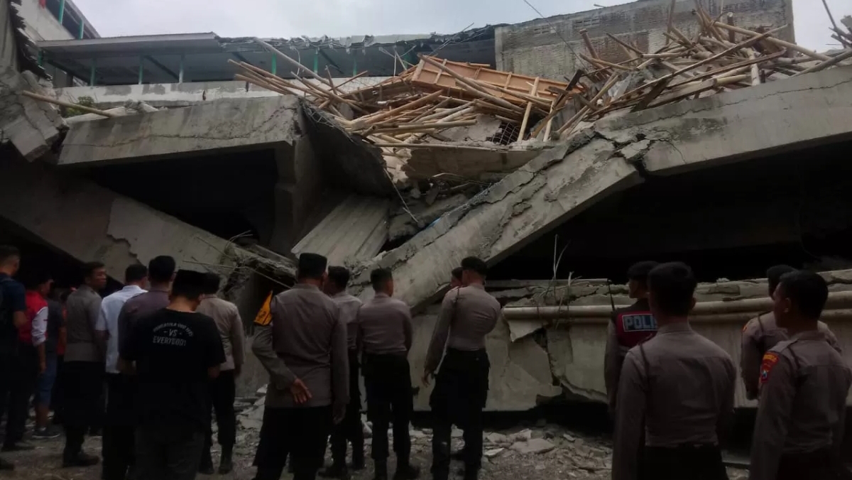 Sejumlah polisi dan warga memantau reruntuhan musala lantai dua Pondok Pesantren Al Khoziny di Buduran, Sidoarjo, Senin (29/9/2025). (Radar Sidoarjo)