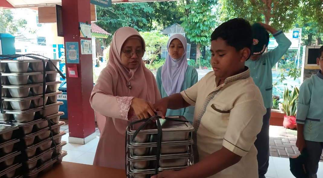 Ilustrasi pembagian Makan Bergizi Gratis (MBG) oleh guru kepada siswa.