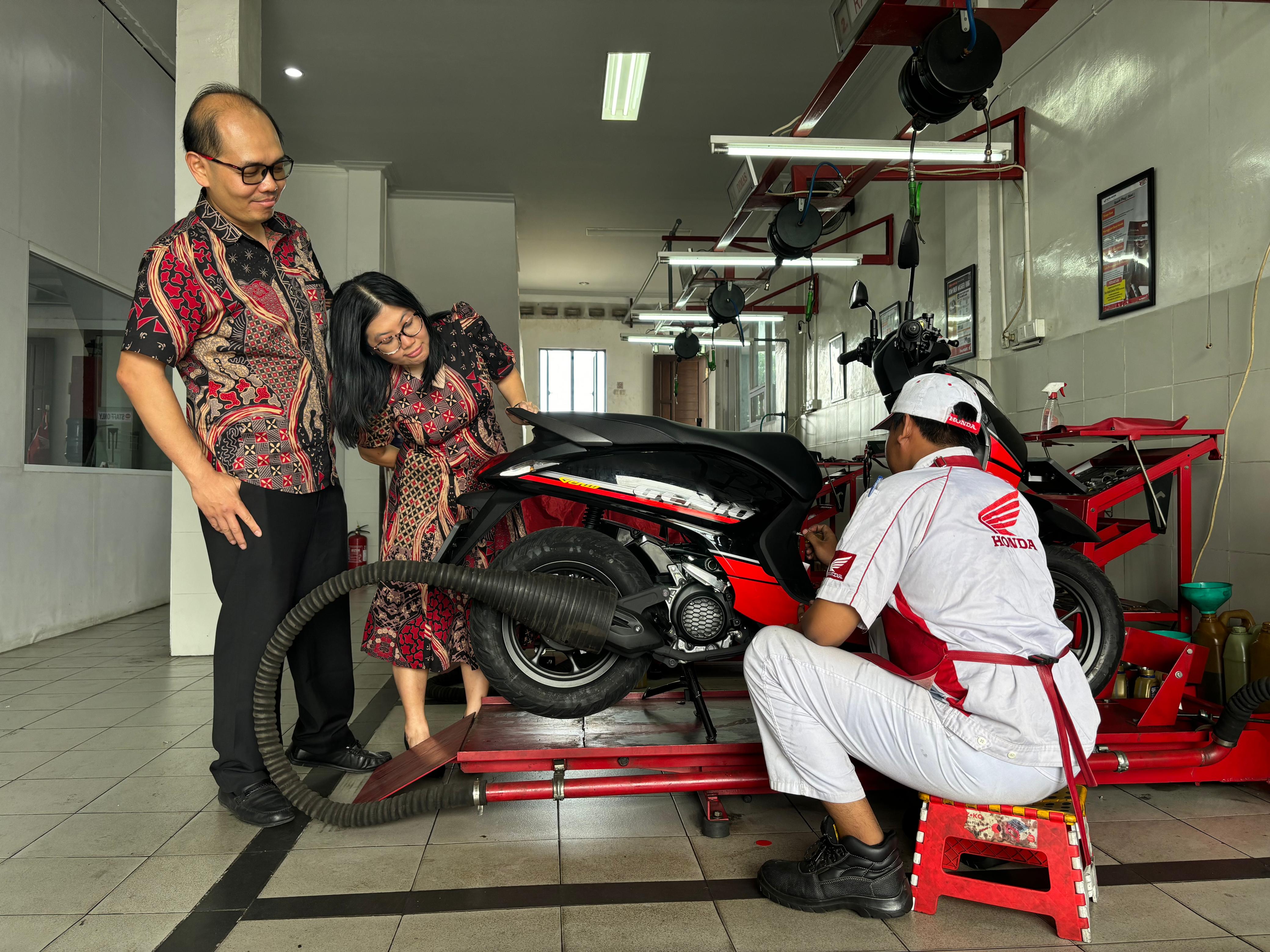 PELAYANAN: Owner AHASS Elvia Jaya, Wielianto Yudha bersama istri melihat teknisinya merawat kendaraan konsumen.