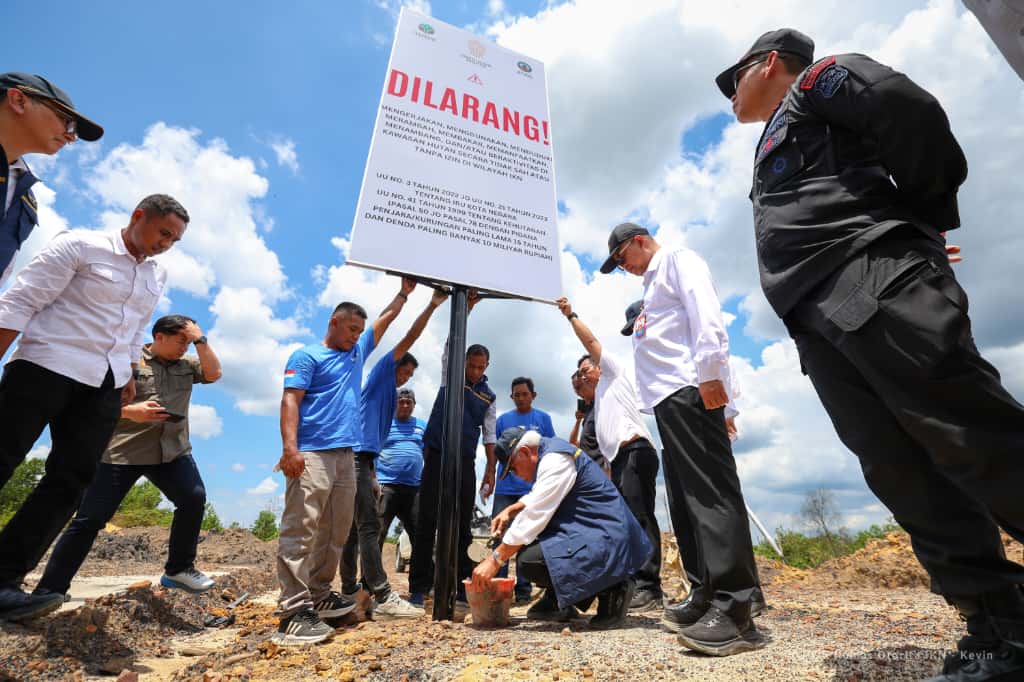 Petugas Satgas Penanggulangan Aktivitas Ilegal bersama Otorita IKN memasang plang larangan di area bekas tambang ilegal Bukit Tengkorak.