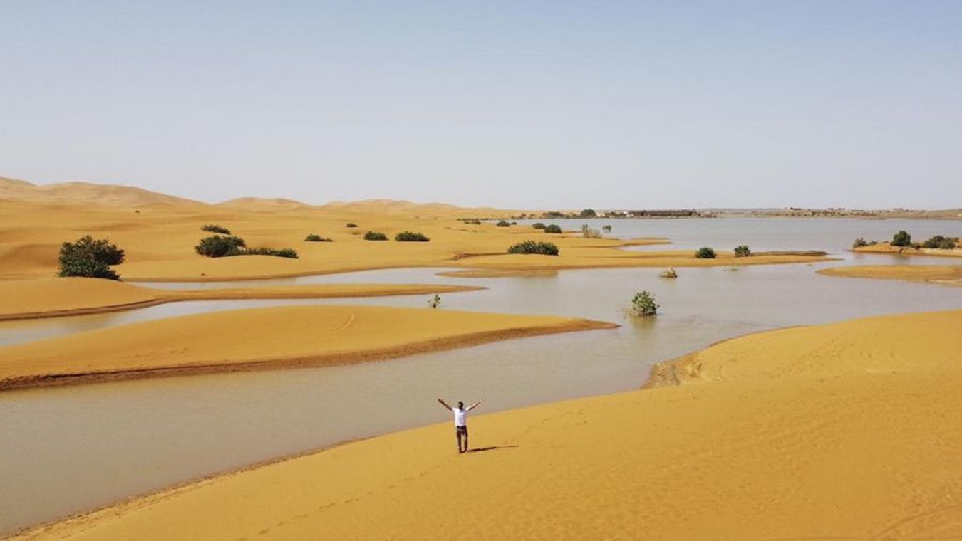 DANAU: Seorang pria  berjalan di bukit pasir di samping danau yang disebabkan oleh hujan lebat di kota gurun Merzouga, dekat Rachidia, tenggara Maroko, 2024.