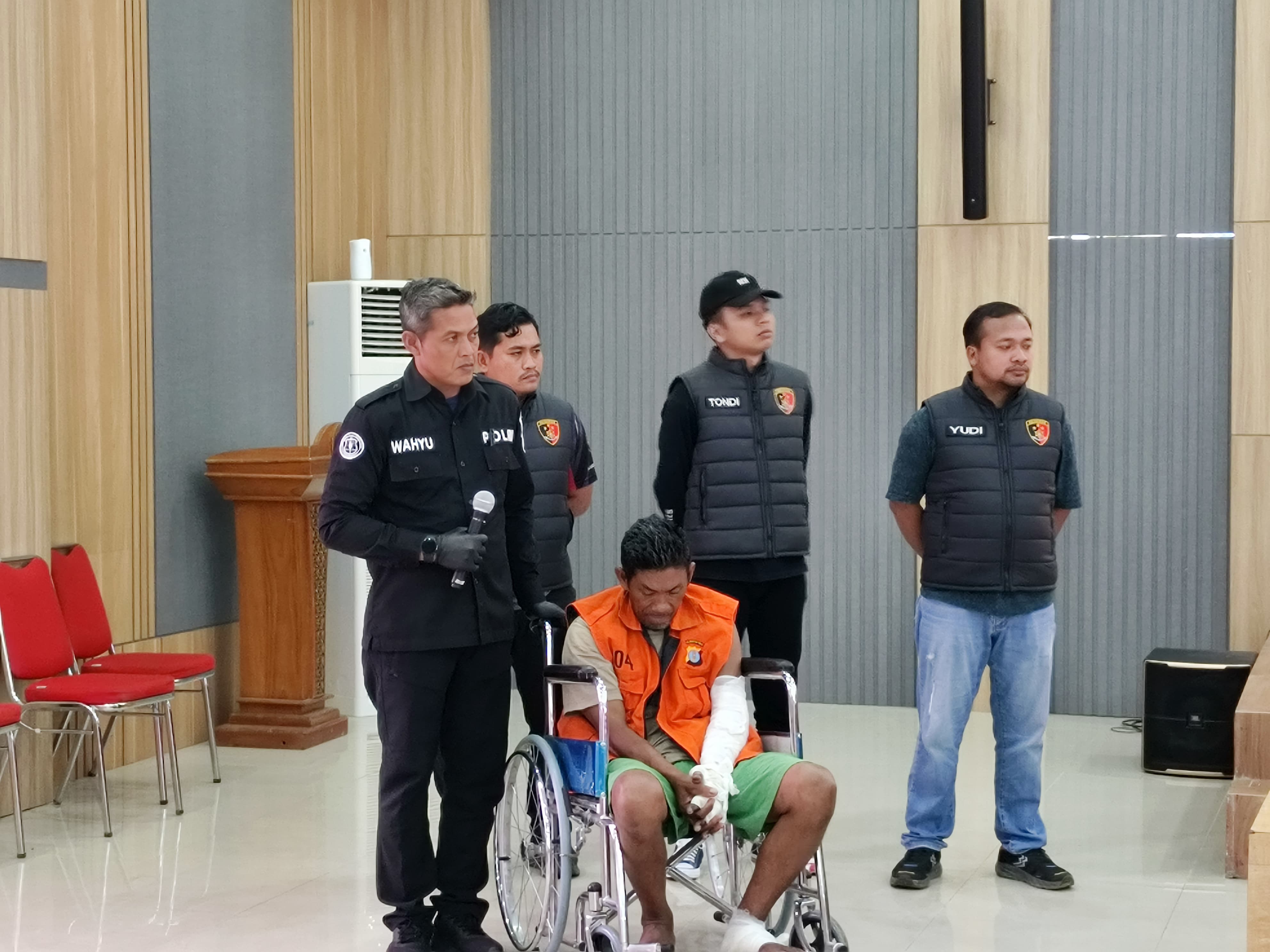 Tersangka kasus pembakaran istri dan anak di Sangatta Selatan duduk di kursi roda saat dihadirkan dalam konferensi pers di Polres Kutim. (JUFRIADI/KP)