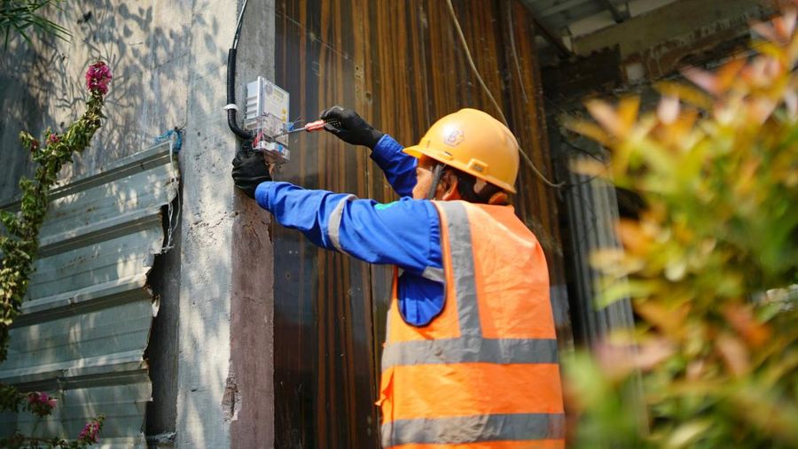 Ilustrasi seorang petugas PLN sedang menambah daya listrik warga.