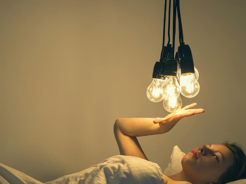 Ilustrasi seorang wanita sedang hendak tidur dengan memakai lampu.