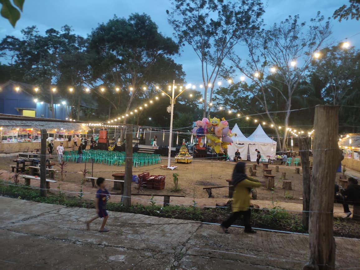 PENUH AKTIVITAS: Lapangan utama Villa Kaning Park dipenuhi cahaya lampu dan aktivitas warga. UMKM berjejer, anak-anak berlarian, sementara area panggung dan ruang publik mulai dimanfaatkan kembali.
