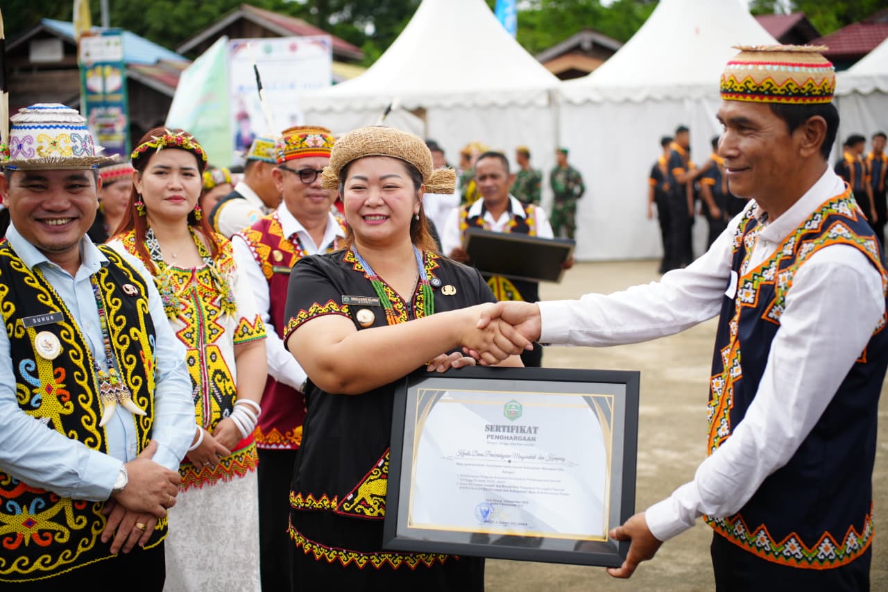 Bupati Mahulu Angela Idang Belawan memberikan penghargaan kepada Kadis DPMK Damianus Tamha di sela Peringatan HUT Ke 12 Mahulu, Senin (15/12). (JODY KRISTIANTO/KP)