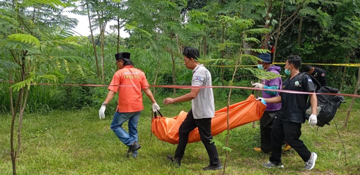 Petugas Unit INAFIS Satreskrim Polres Tulungagung mengevakuasi jenazah pria tanpa identitas yang ditemukan di kebun sengon Desa Gendingan, Kecamatan Kedungwaru, Tulungagung. (FOTO: IST)