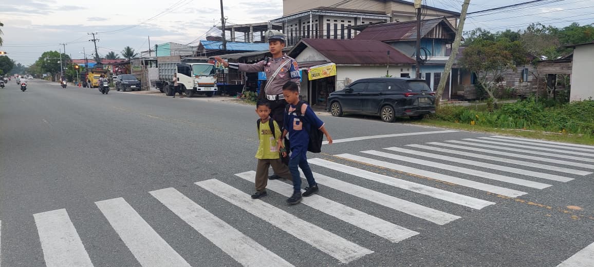 BANTU: Personel Satlantas Polres PPU saat menyeberangkan pelajar menuju sekolah.