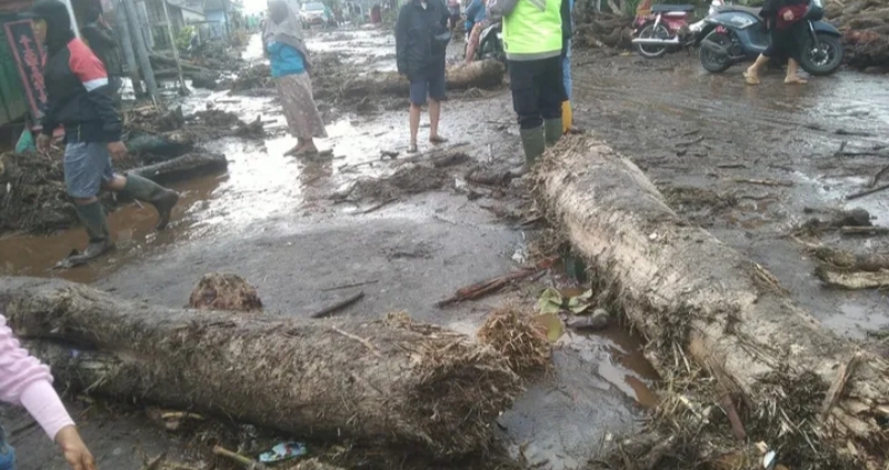 Petugas BPBD bersama warga membersihkan material lumpur dan batang kayu yang menutup jalan usai banjir bandang di kawasan lereng Gunung Slamet, Purbalingga, Jawa Tengah, Sabtu (24/1/2026). (Foto ist)
