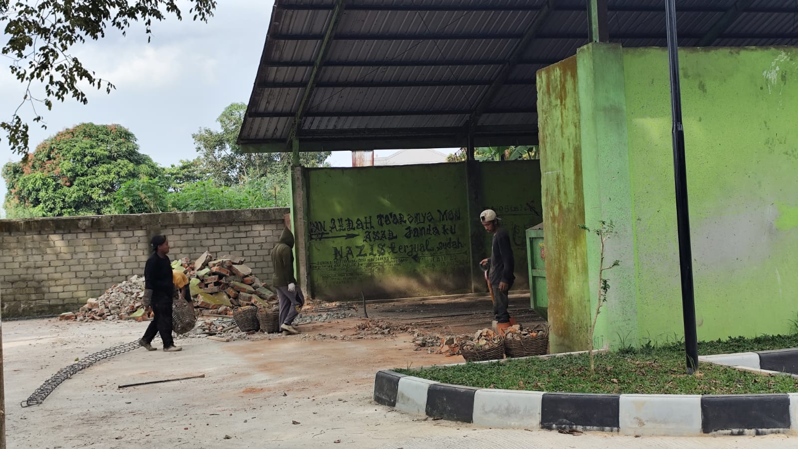 REKAYASA: Beberapa pekerja terlihat membongkar dinding belakang TPS Sungai Keledang, karena akan menjadi akses baru untuk membuang sampah warga sekitar, Senin (26/1).
