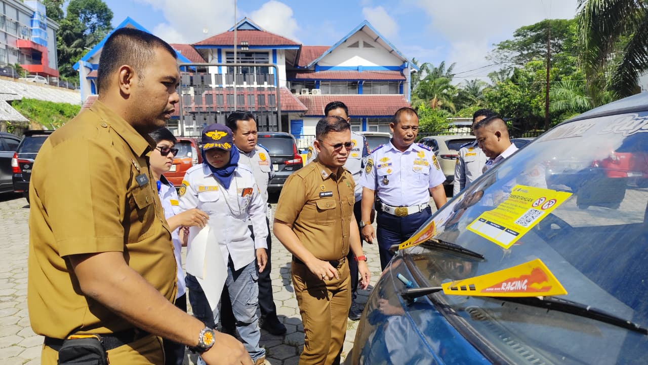 HMT Manalu (tengah) memasang stiker pemberitahuan pelanggaran larangan parkir, di salah satu mobil yang telah diamankan di kantor Dishub Samarinda, Selasa (3/2/2026).  &nbsp;