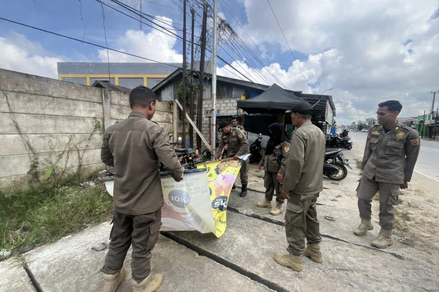 Tim Satpol PP kecamatan menertibkan spanduk di warung makan tepi jalan di Kelurahan Rapak Dalam, Selasa (3/2).