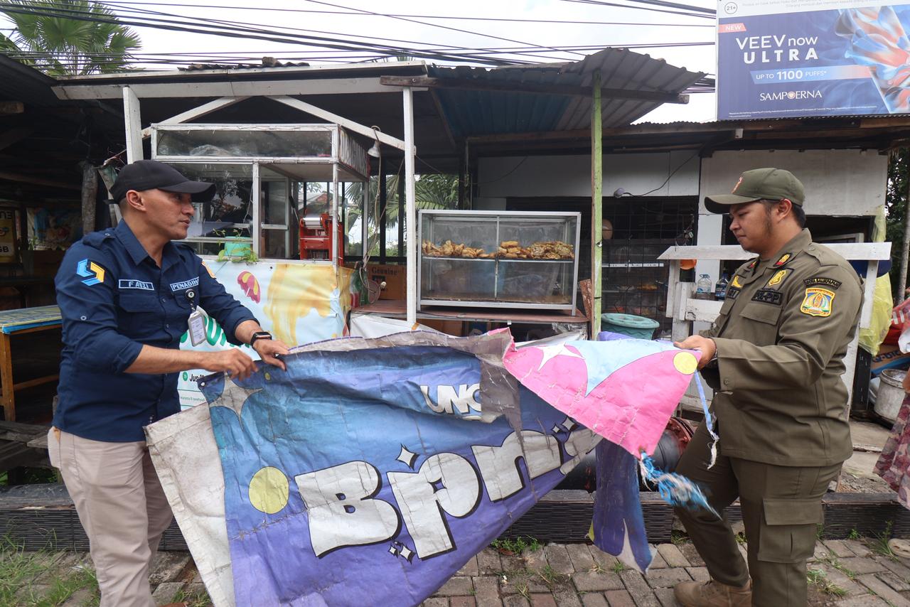 Petugas membersihkan spanduk yang merusak pemandangan kota.