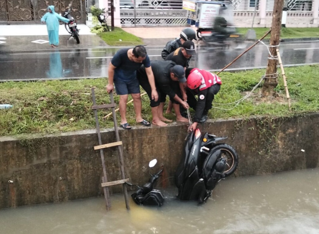 EVAKUASI: Petugas gabungan mengevakuasi sepeda motor yang tercebur ke sungai.