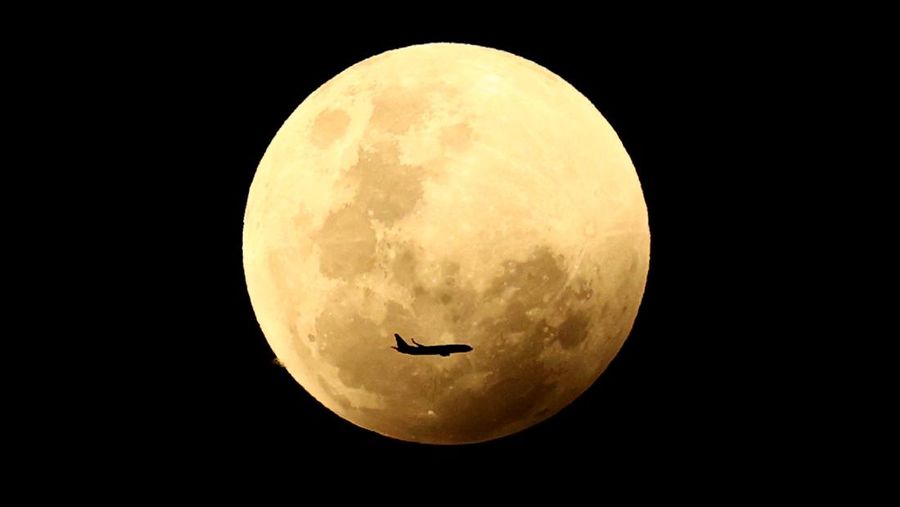 BULAN: Sebuah pesawat tampak melintasi di depan bulan purnama jelang gerhana total November 2022.