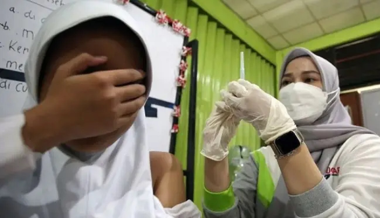 VAKSIN: Seorang dokter sedang menyiapkan vaksin campak untuk disuntikkan ke seorang anak murid sekolah dasar.