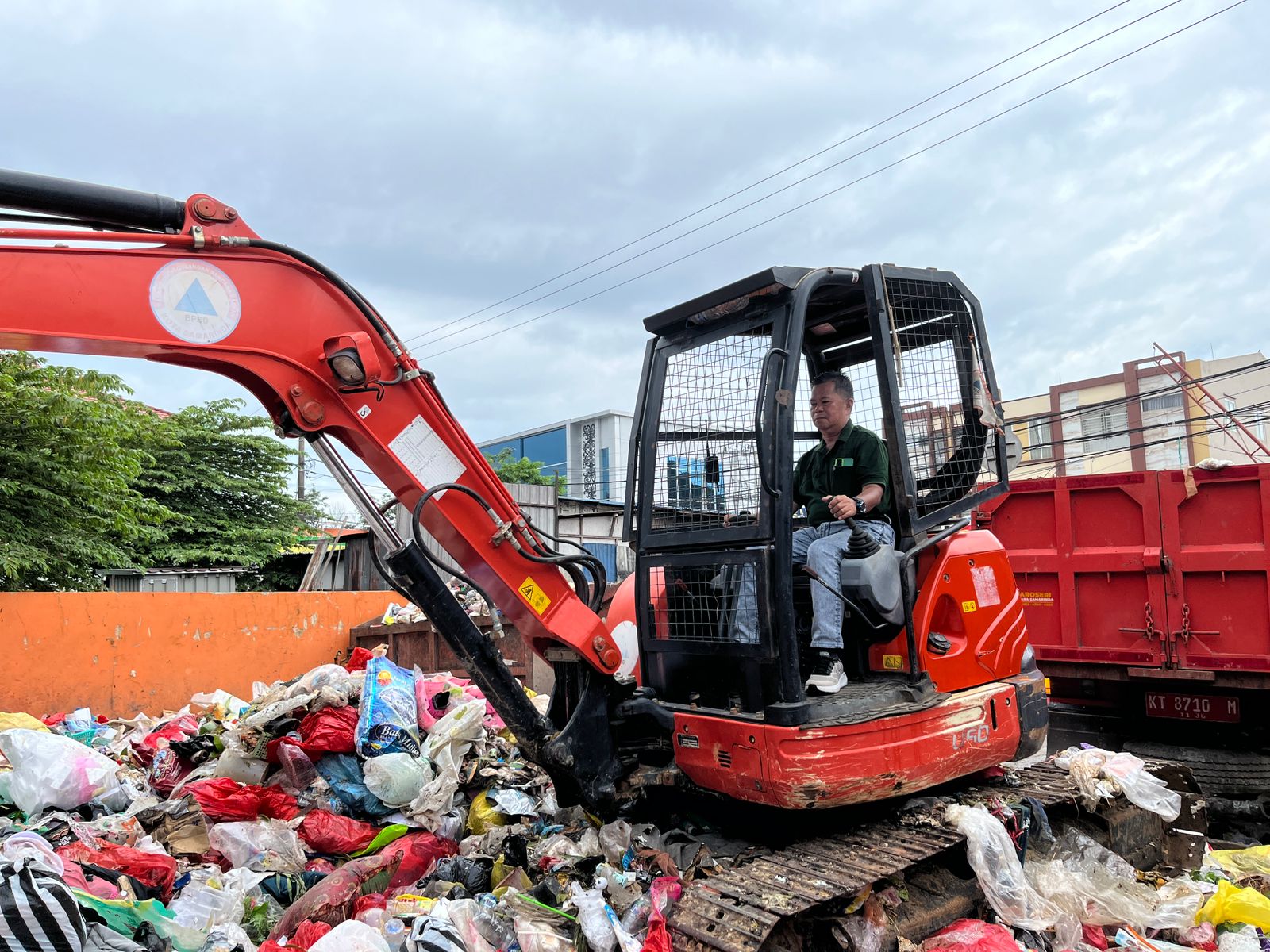 IKUT JAGA: Marnabas mengoperasikan ekskavator mini menaikkan sampah ke atas kontainer, untuk percepatan pembuangan sampah menuju TPA.  