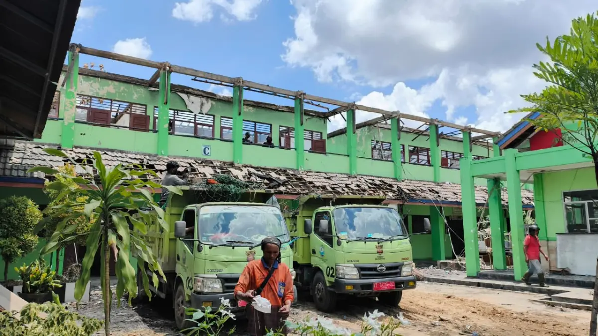 PEMBERSIHAN: Petugas gabungan membersihkan puing kebakaran di SMPN 2 Samarinda, Minggu (5/4). HAFIZ/KP