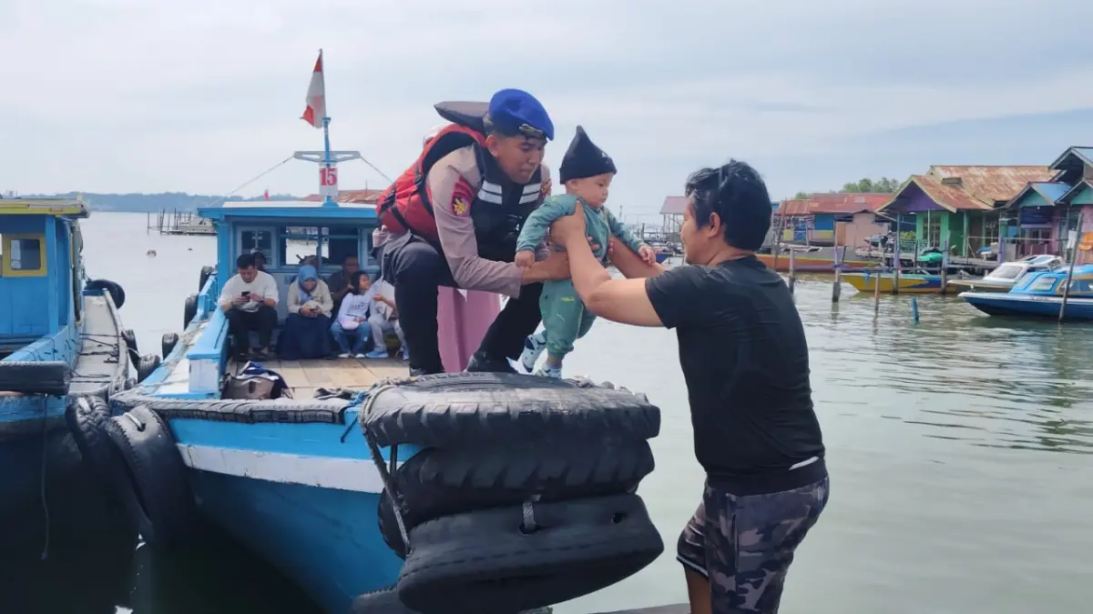 MENOLONG: Personel Satpolairud Polres PPU membantu menurunkan bayi dari kendaraan moda air setibanya dari Balikpapan di Pelabuhan Kelotok Penajam, PPU. (humas polres ppu/kp)