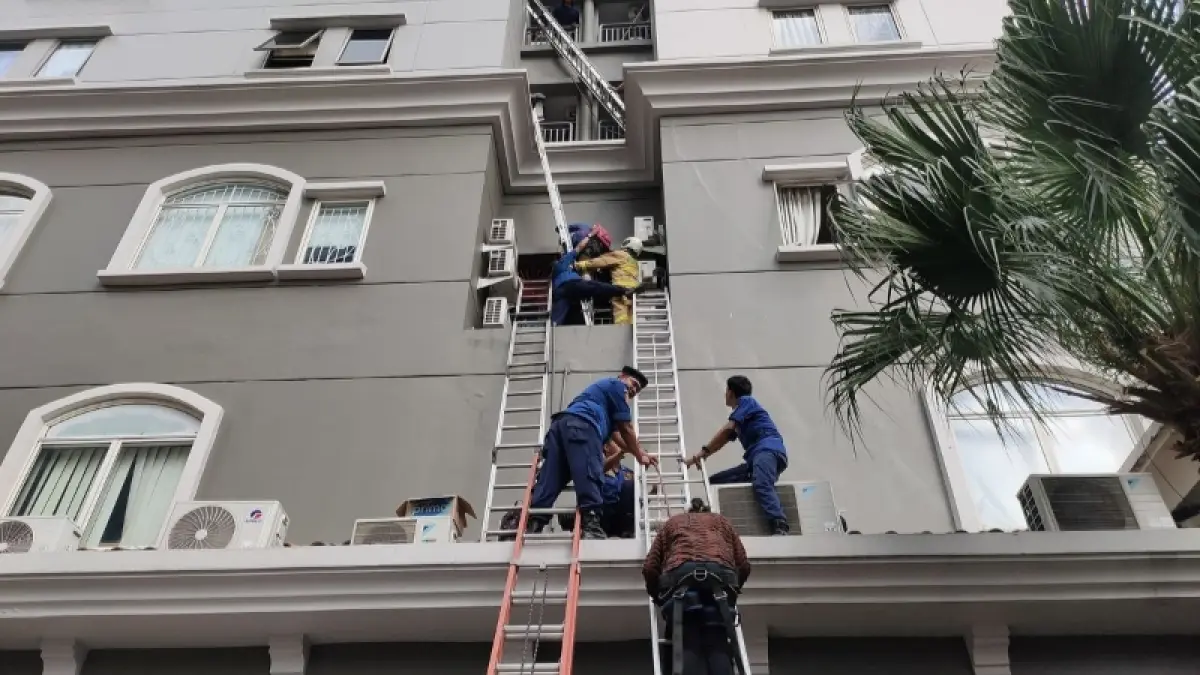 Petugas mengevakuasi penghuni melalui tangga darurat dari gedung apartemen di Tanjung Duren saat kebakaran terjadi. 