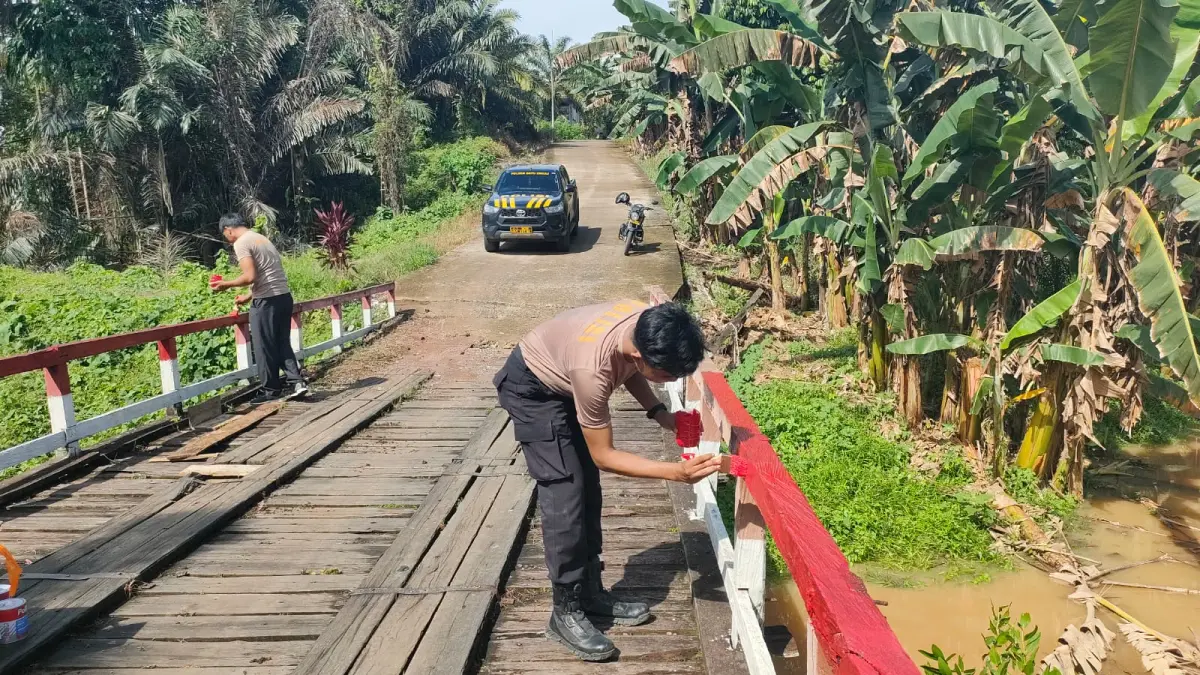 Personel Polsek Batu Engau bersama warga memperbaiki dan mengecat jembatan di RT 010 Desa Kerang, Paser.