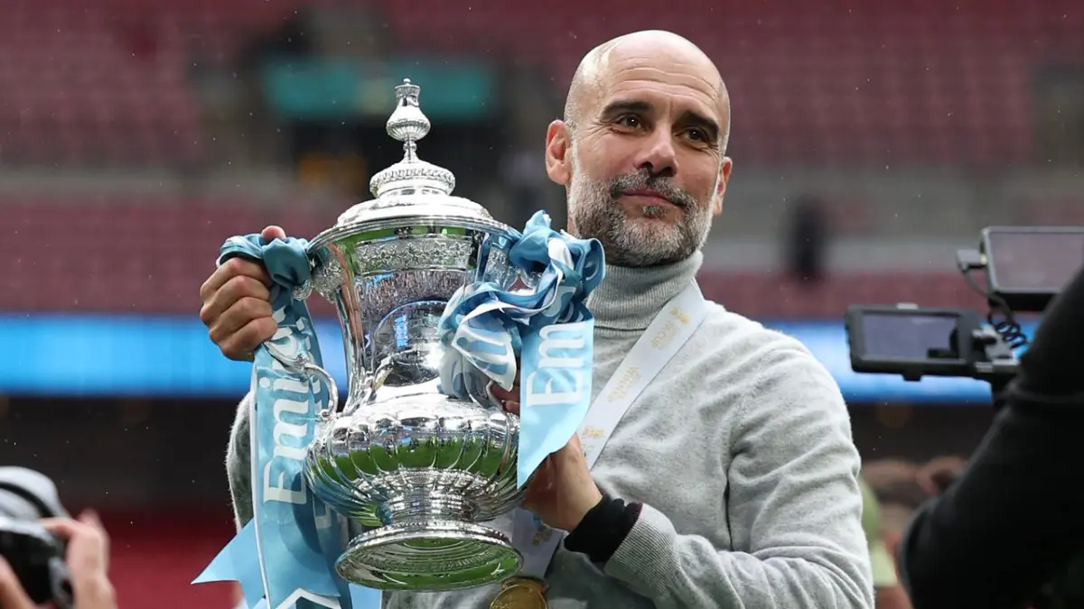 Pep Guardiola membawa trofi Piala FA di lapangan Wembley setelah Manchester City keluar sebagai juara usai menundukkan Chelsea. (Adrian Dennis / AFP)