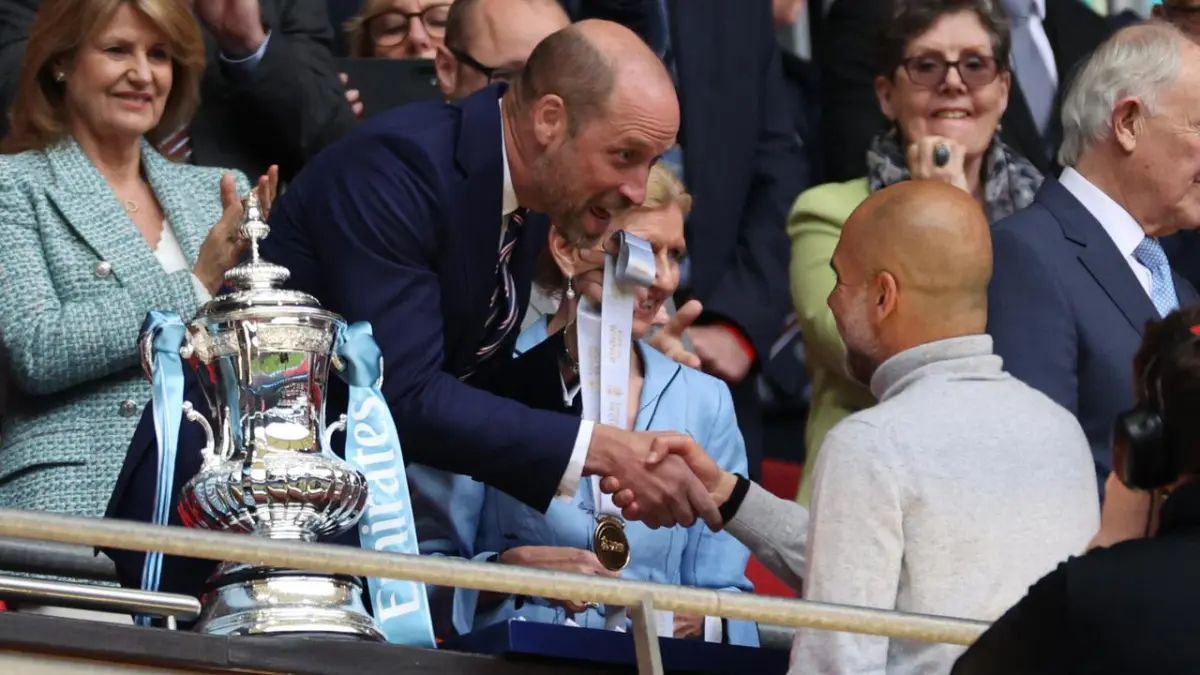 Pep Guardiola membawa trofi Piala FA di lapangan Wembley setelah Manchester City keluar sebagai juara usai menundukkan Chelsea. (Adrian Dennis / AFP)